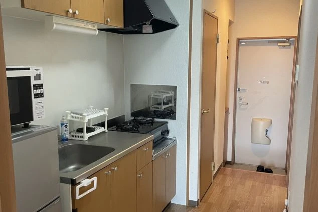 リゾートバイトの寮のキッチンの画像。シンクとコンロ、冷蔵庫、電子レンジが備え付けられている。リゾートバイトの寮の共用キッチンの画像。