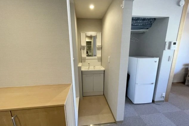 リゾートバイトの完全個室寮の洗面台・冷蔵庫・収納スペースの画像。