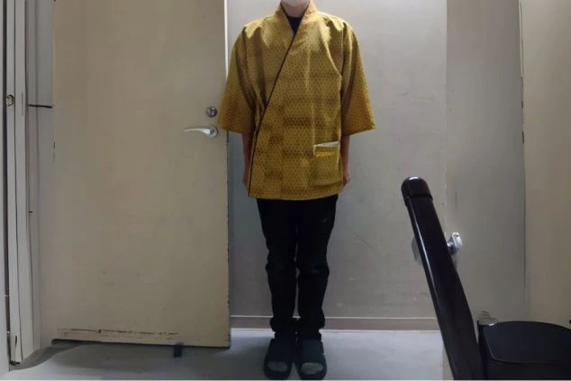 黄色の作務衣に黒いパンツを着用した、リゾートバイトの裏方スタッフの制服。裏方業務や清掃など、お客様の目に触れない場所での仕事に興味がある方に訴求する画像。