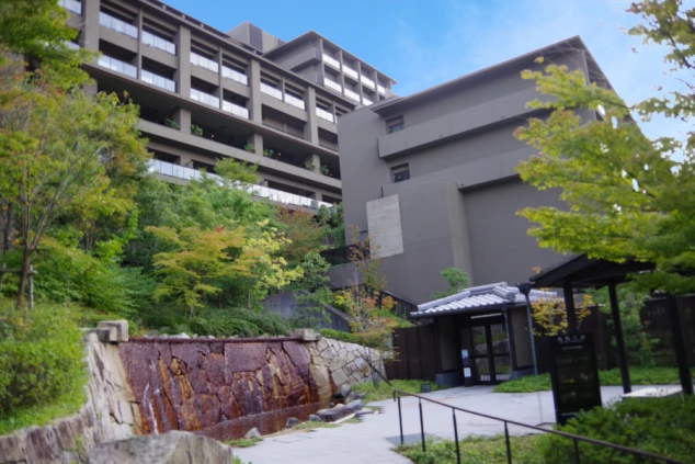 木々の緑に囲まれた、モダンな和風建築のホテル外観。