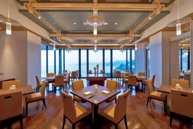 ホテルのダイニングの画像。大きな窓からは海が一望でき、温かみのある木目調のテーブルと椅子が並んでいる。リゾートバイトの仕事内容を表す、ホテルのダイニングの画像。