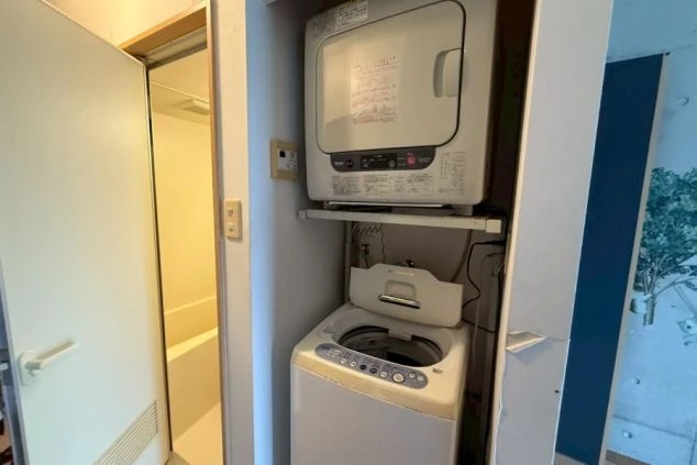 寮の洗濯スペース。全自動洗濯機と、その上に衣類乾燥機が設置された、二段重ねの洗濯設備。
