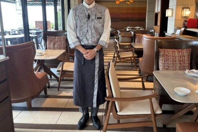 リゾートバイトの仕事風景を表現するイメージ画像。レストランのホールの仕事で着用する、花柄のシャツと黒いエプロン。