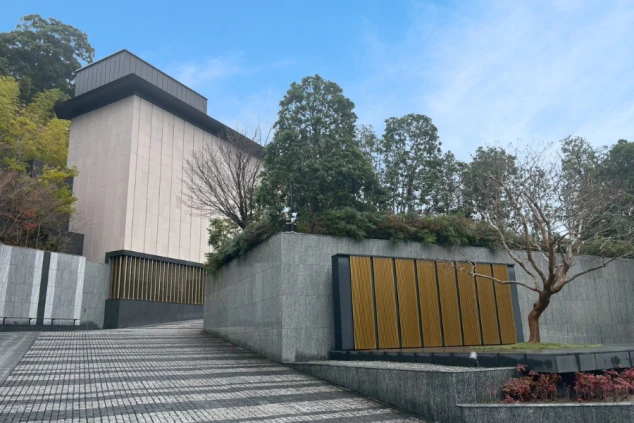 石畳のスロープと高い塀が続く、重厚な外観。