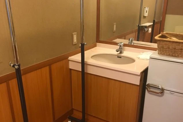 リゾートバイトの館内寮にある洗面台と鏡。身だしなみを整えやすいスペースで、快適な寮生活を送れることを示す画像。