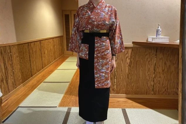 温泉旅館の女性スタッフ用制服画像。色鮮やかなオレンジ色の二部式着物。