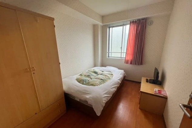 リゾートバイトの個室寮の室内。シングルベッド、テレビ、クローゼットが設置されており、プライベート空間が確保された寮の部屋の画像。