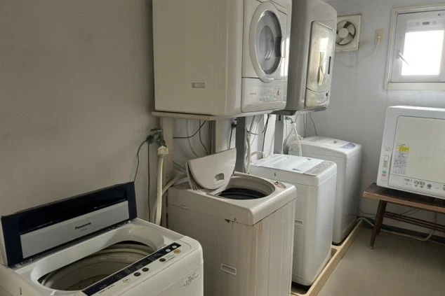 リゾートバイトの寮にある共用ランドリースペース。洗濯機と乾燥機が複数台設置されており、長期滞在でも衣類の手入れに困らない設備の寮画像。