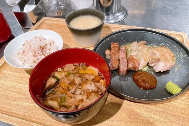 リゾートバイトの賄い画像。豚肉のステーキと野菜、ご飯、味噌汁が揃った、バランスの良い定食。