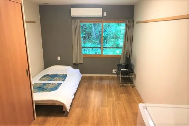 リゾートバイトの寮に完備された個室。窓から自然が見える明るい部屋で、エアコンとテレビがあり、快適な一人暮らしが可能。