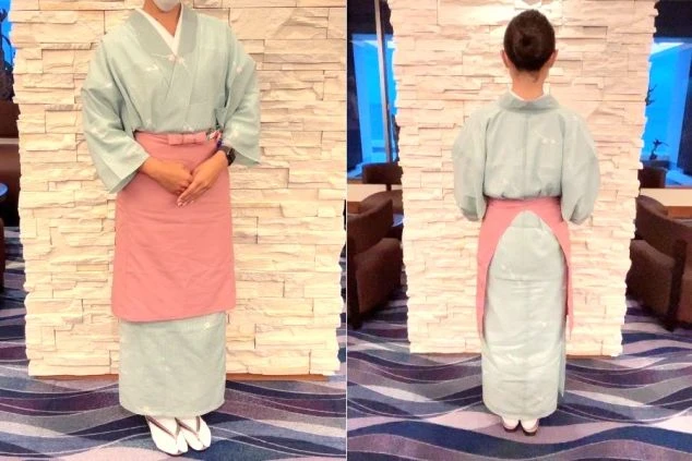 仲居スタッフの制服。淡い緑色の着物にピンクのエプロン姿。
