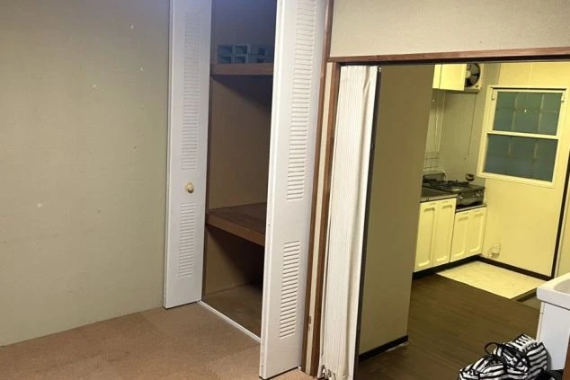 白い扉のクローゼットと、その奥にキッチンが見える室内の様子。