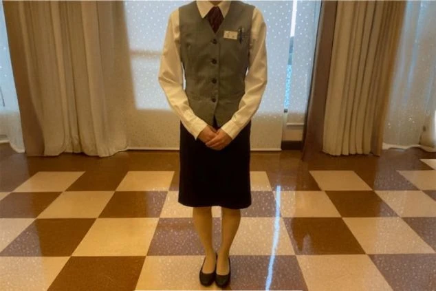 白シャツにグレーのベスト、ネクタイ、黒いスカートを着用した女性スタッフの制服姿。ホテルのフロントやレストラン業務向けの、清潔感のある装い。
