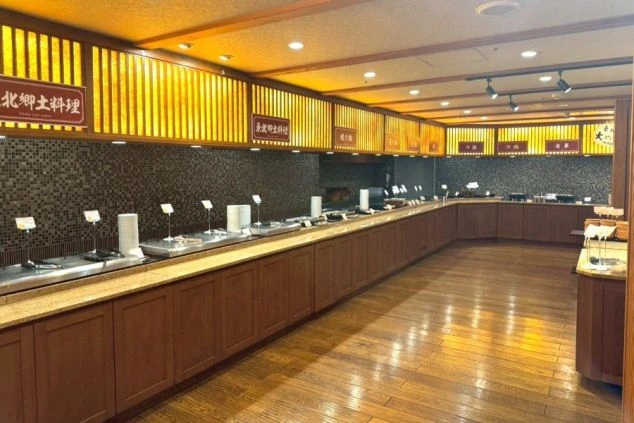 鳴子温泉駅の看板。背後には緑豊かな山々が広がり、温泉地らしい自然の雰囲気を演出。リゾートバイトの勤務地として、自然と温泉の魅力をアピール。