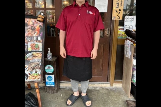 飲食店で働く男性スタッフの制服。赤色のポロシャツと黒いエプロンを着用した、スポーティーでカジュアルなスタイルです。