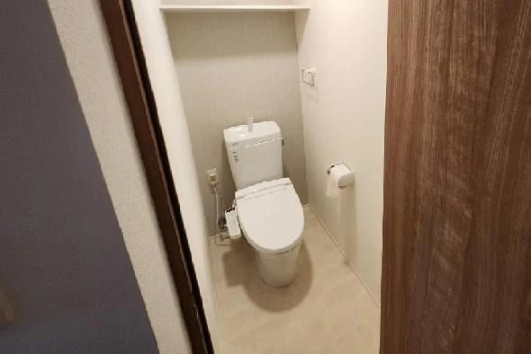 白い壁と床のシンプルな空間に、温水洗浄機能付きの洋式トイレ。