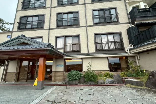 立派な瓦屋根の車寄せと、石畳の敷地、和の趣がある多階建ての建物が並んでいます。