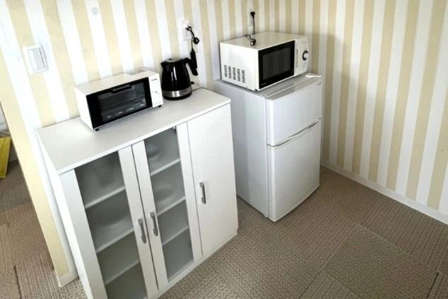 電子レンジ、冷蔵庫、電気ケトル、食器棚が揃ったリゾートバイト寮の画像。生活に必要な家電がひと通り完備。