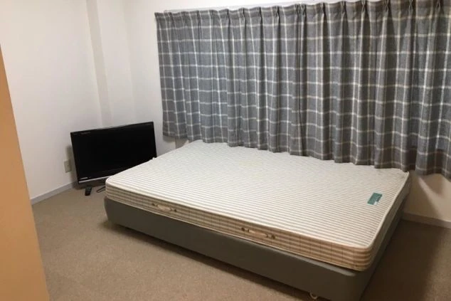 男子寮の部屋の中の画像。ベッドとテレビが置かれている。