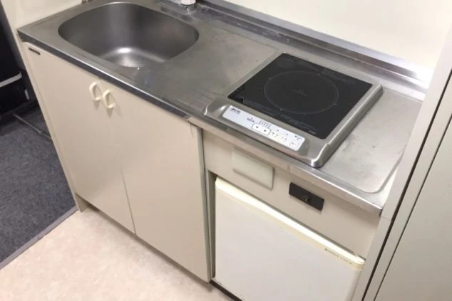 女子寮のミニキッチンの画像。IHコンロ、シンク、冷蔵庫が見える。