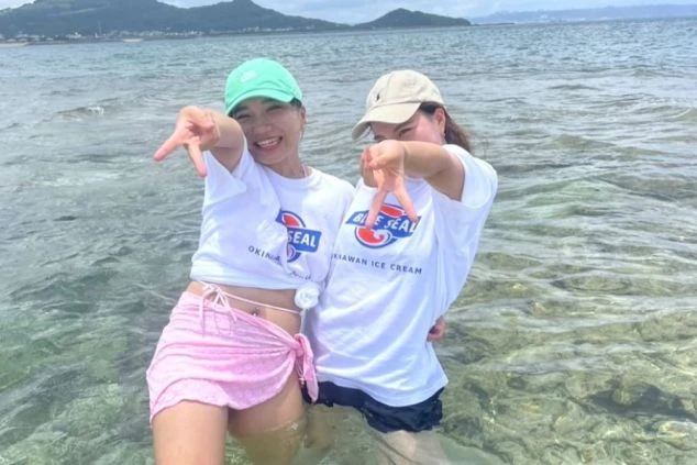 沖縄の美しいビーチで、笑顔でポーズをとる2人の女性