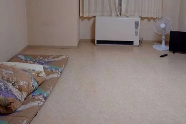 リゾートバイトの寮の洋室。床に布団が敷かれ、ヒーターと扇風機が置かれています。