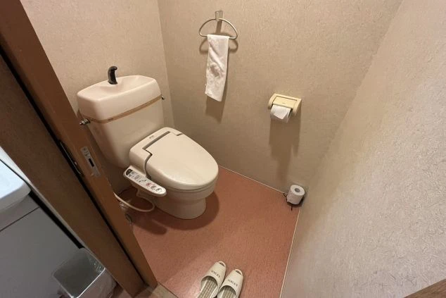 トイレスリッパが床に置かれた、温水洗浄便座付きのトイレ。