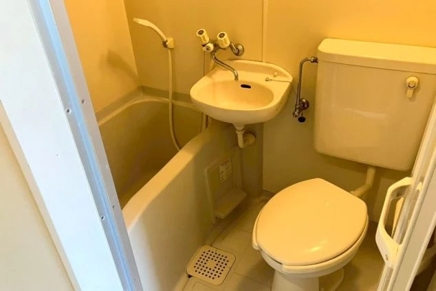 浴槽とトイレ、洗面台が一体となった寮のユニットバスの画像。