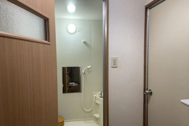 リゾートバイトの寮のバスルームの画像。白い壁と床で清潔感があり、バスタブとシャワーが備え付けられている。リゾートバイトの寮の風呂場の画像。