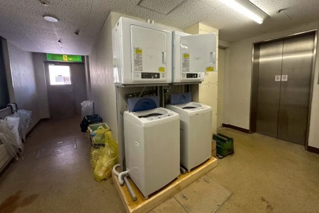 長期滞在も安心な寮内のランドリールームの画像。洗濯機と乾燥機が複数台設置。