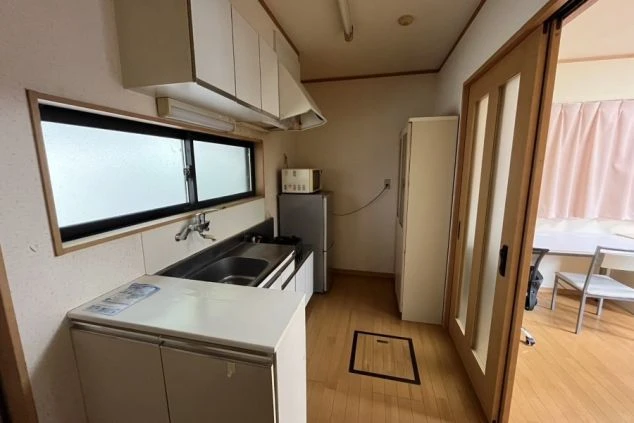 リゾートバイト寮の室内キッチン。冷蔵庫や電子レンジ、収納棚が揃い自炊もできる便利な生活環境。