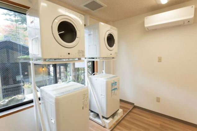 群馬県草津温泉でリゾートバイトするスタッフが住む寮のランドリールームの画像。洗濯機と乾燥機が2台ずつ設置されている。