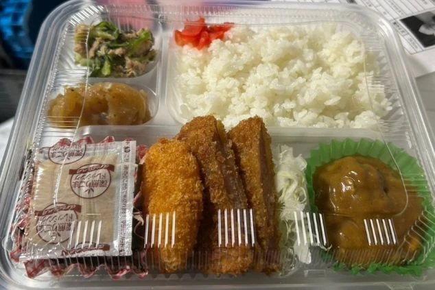 リゾートバイトのまかない画像。ごはんや揚げ物が入ったボリュームたっぷりのお弁当。