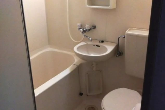 寮のユニットバス。浴槽、シャワー、トイレ、洗面台が一体となった清潔な空間が映る。