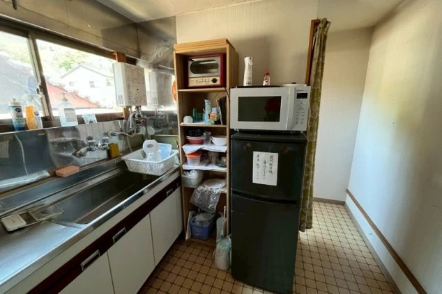 リゾートバイトの寮にあるキッチンの画像。冷蔵庫、電子レンジ、トースター、シンクが完備された共用スペース。