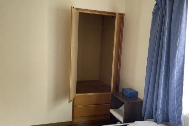 部屋の隅にある木製のクローゼット。扉が開いており、中には何もない。