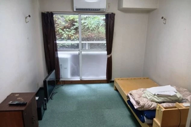 リゾートバイトの寮の部屋の画像。ベッドとテレビ、そして窓が写っている。窓からは光が差し込み、明るい雰囲気の部屋であることがわかる。リゾートバイトの寮の部屋の画像。