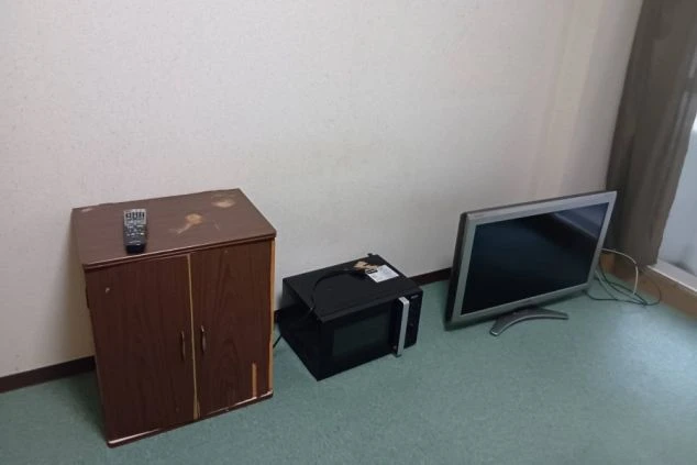 リゾートバイトの個室寮の部屋の画像。部屋にはテレビ台とテレビ、電子レンジが置かれている。リゾートバイト中の生活に役立つ家電が揃っていることがわかる画像の画像。