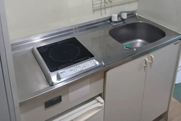 リゾートバイトの寮のキッチンの画像。シンクとIHクッキングヒーターが備え付けられており、自炊ができる。リゾートバイトの寮の共用キッチンの画像。