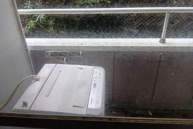 リゾートバイトの寮のベランダに置かれた洗濯機の画像。窓から撮影しており、洗濯機や物干し竿が備え付けられていることがわかる。リゾートバイトの寮の共用スペースの画像。