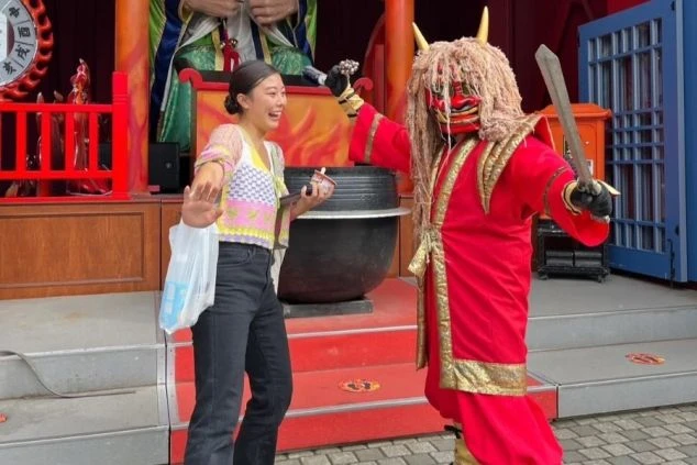 登別温泉で迫力ある「なまはげ」のような鬼のキャラクターと記念撮影をする女性ワクトリスタッフの画像。