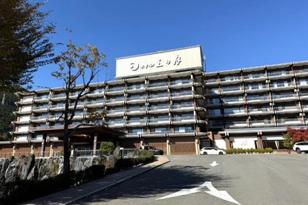 青空の下にそびえ立つ、滝のある庭園を備えた鬼怒川にあるホテルの外観の画像。