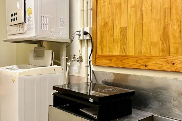 リゾートバイトの館内寮の共用設備の画像。洗濯機・乾燥機・IHキッチンがある。
