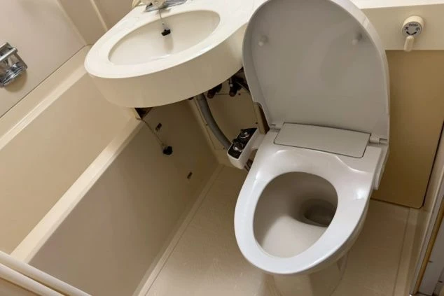 寮のユニットバスのトイレ。ウォシュレット付きで、プライベートが確保された清潔な設備。