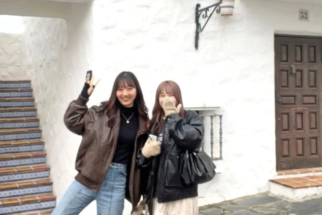 白壁と木製の扉が印象的な異国情緒あふれる建物の前で、笑顔でポーズをとる2人の女性。