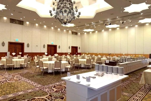 ホテル志摩スペイン村の宴会場を利用したバイキング会場。高い天井には豪華なシャンデリアが輝き、円卓のテーブル席と料理が並ぶカウンターが整然と配置されています。