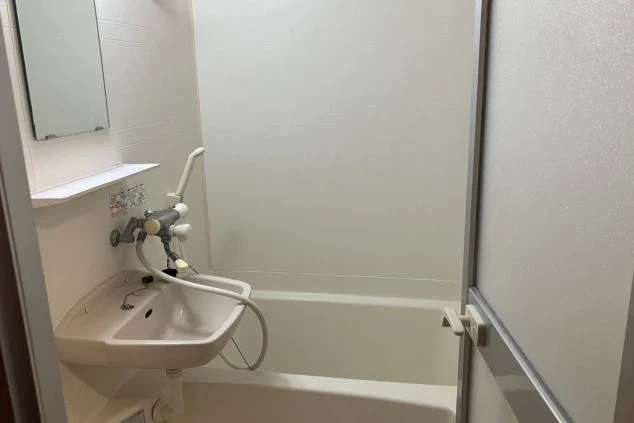 寮に完備された清潔なユニットバス。シャワーと浴槽があり、疲れた体をゆっくり休められることをアピールする画像。