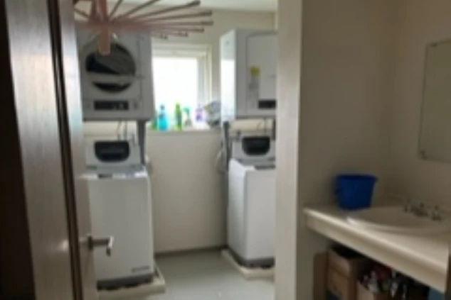 リゾートバイトの寮の洗濯室。洗濯機と乾燥機が２セット、洗面台、物干しハンガーが映る。