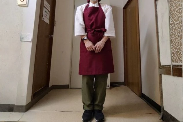 白シャツにエンジ色のエプロン、カーキのパンツを合わせた制服画像。