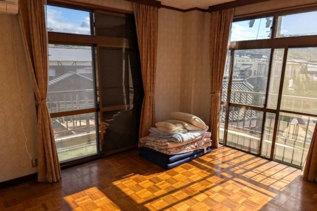 日当たりの良いフローリングの個室画像。大きな窓があり、布団セットも完備された、明るく広々とした淡路島でのリゾートバイト居住スペース。